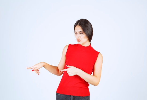 La chica de camisa roja se ve triste y decepcionada.