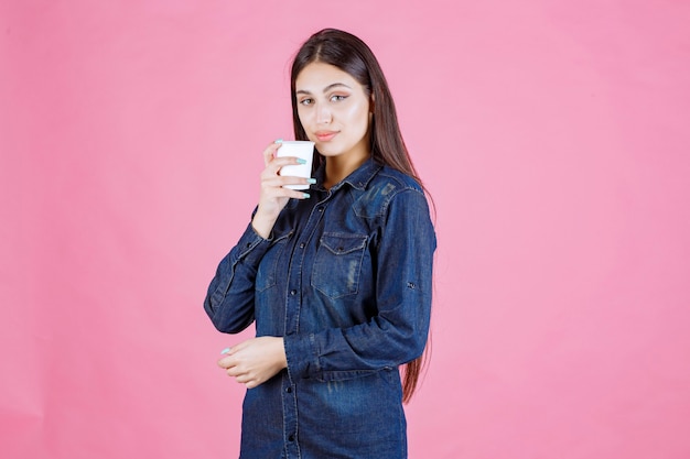 Chica en camisa vaquera bebiendo una taza de café