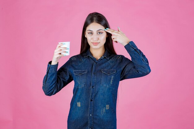 Chica en camisa vaquera disfrutando de una taza de café desechable