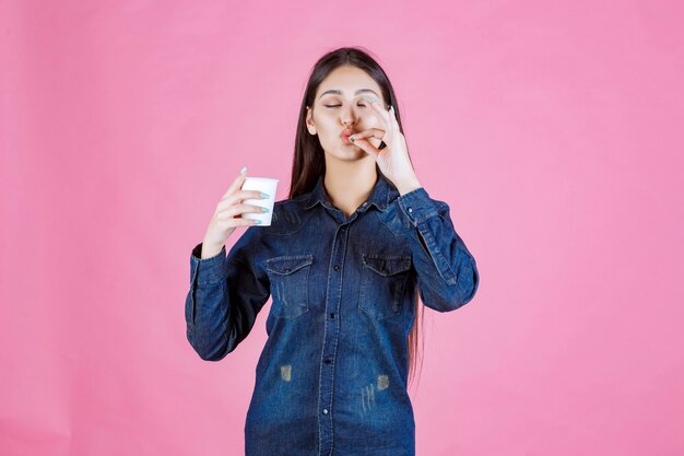 Chica en camisa vaquera tomando café y disfrutando del sabor