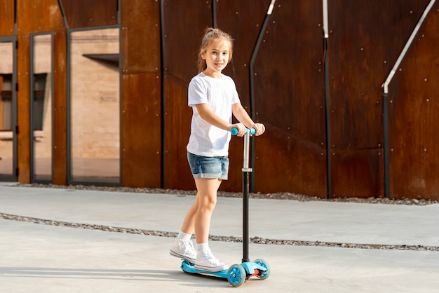 Chica en camiseta blanca montando scooter azul