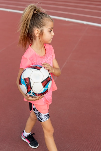 Chica en camiseta rosa sosteniendo una pelota