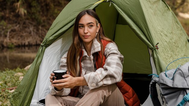 Chica de camping en el bosque sosteniendo una taza