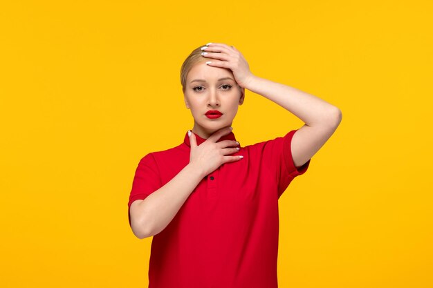 Chica cansada del día de la camisa roja tocando su cabeza y garganta en una camisa roja sobre un fondo amarillo