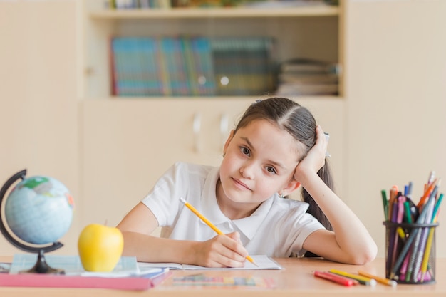 Foto gratuita chica cansada sentado en el escritorio de la escuela