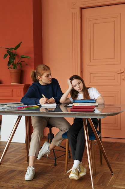 Foto gratuita chica cansada de tiro completo sentada en el escritorio