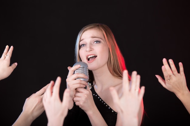 Foto gratuita chica cantando y manos levantadas de público