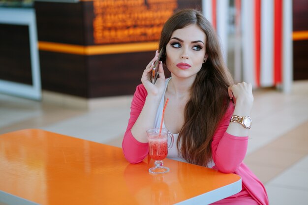 Chica con cara seria hablando por teléfono sentada en un restaurante