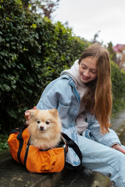 Chica cargando cachorro en bolsa vista lateral