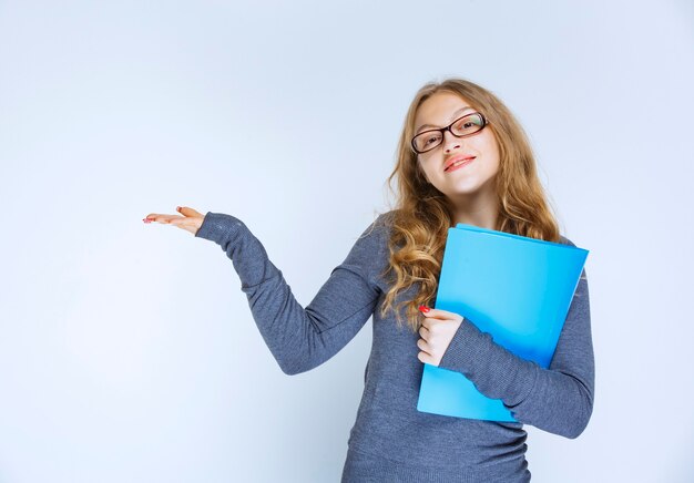 Chica con una carpeta azul apuntando a su colega.