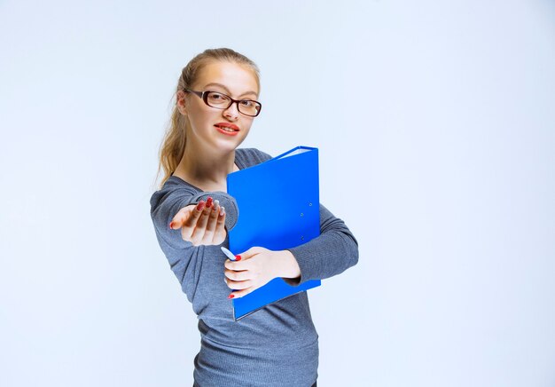 Chica con una carpeta azul notando a su colega.