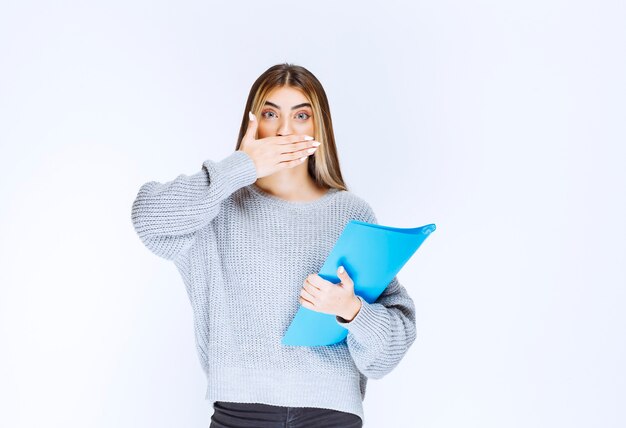 La chica con una carpeta azul parece confundida y aterrorizada.