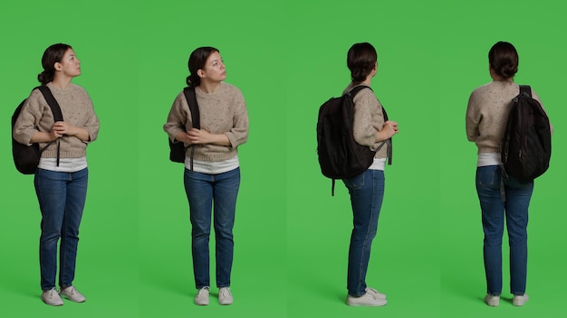 Chica casual con mochila y posando en el fondo del estudio, con bolsas de viaje para el viaje. Cuerpo completo de adulto joven parado sobre fondo de pantalla verde, actividad de ocio en cámara.