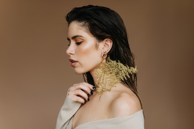 Chica caucásica complacida mirando hacia abajo. Triste mujer de pelo negro posando con planta.