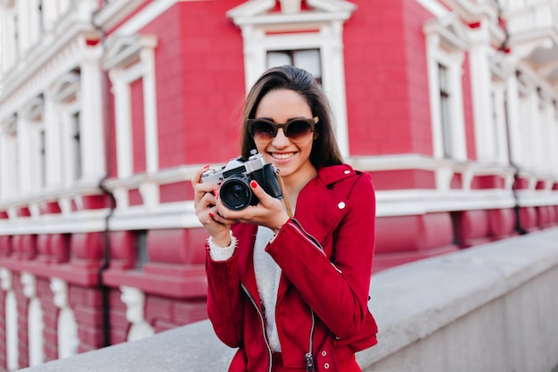 Chica caucásica inspirada posando con sonrisa feliz después de la sesión de fotos en la calle