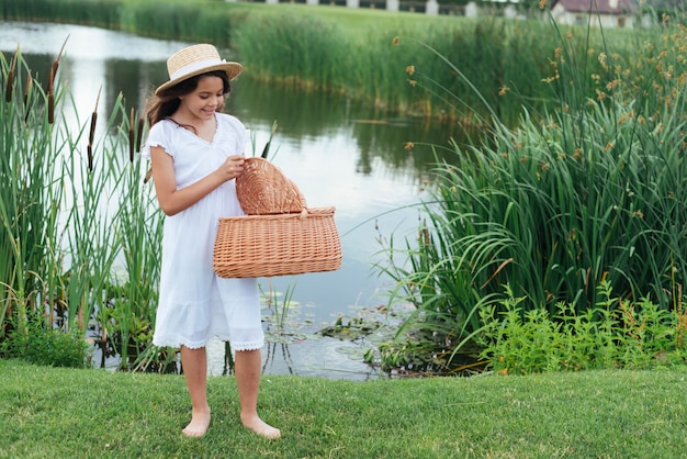 Chica con cesta de picnic junto al lago