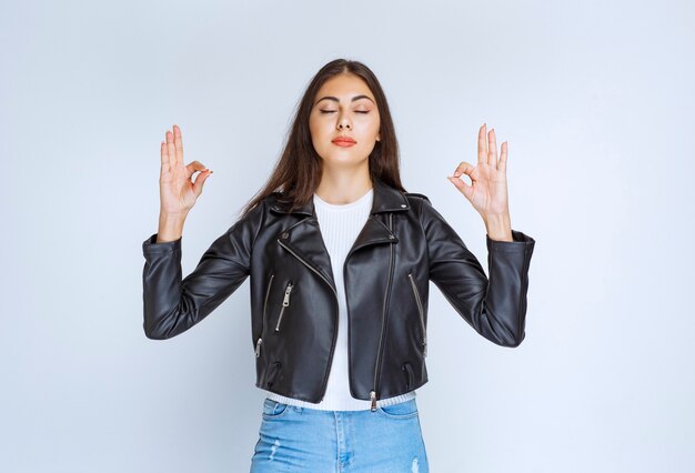 Chica con chaqueta de cuero mostrando signo de disfrute.