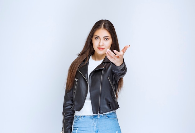 Chica con chaqueta de cuero presentando a alguien a un lado.