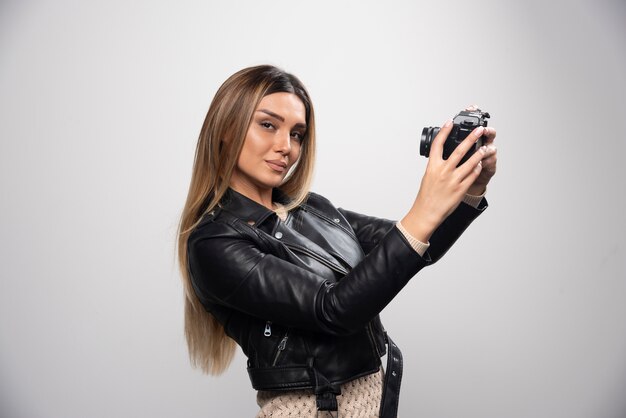 Chica con chaqueta de cuero tomando sus fotos en posiciones elegantes y positivas.