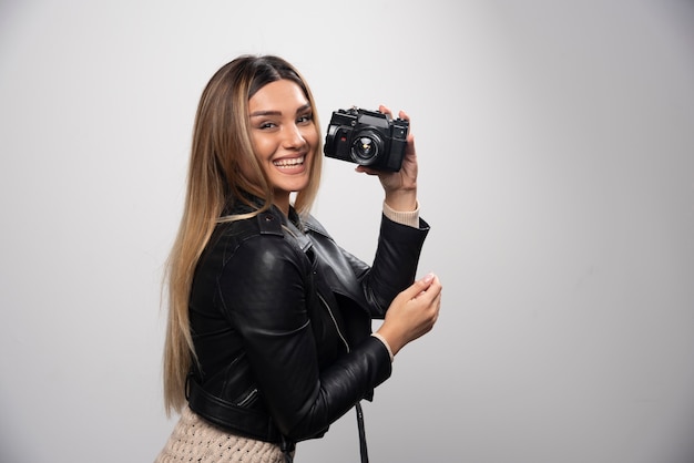 Chica con chaqueta de cuero tomando sus fotos en posiciones elegantes y positivas.