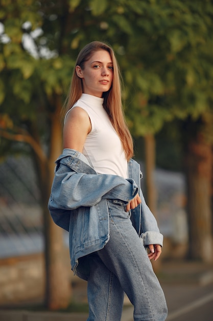 Chica en una chaqueta de jeans azul en una ciudad de verano