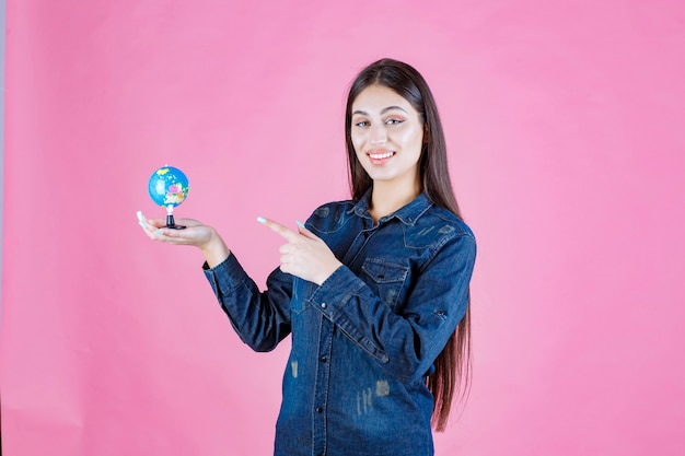 Chica en chaqueta de mezclilla sosteniendo un globo y apuntando a él