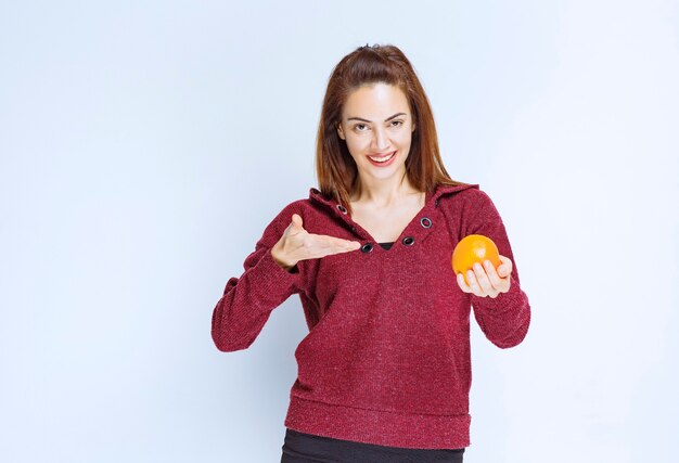 Chica de chaqueta roja sosteniendo una naranja