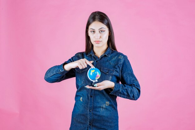 Chica en chaqueta vaquera adivinando lugares del mundo