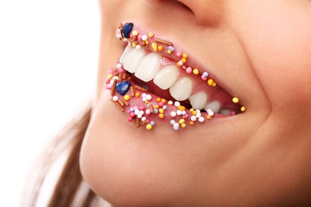 Chica con coberturas de caramelo en los labios. Dulces labios de azúcar