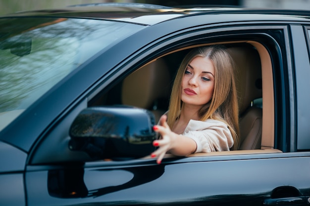 Chica en coche arreglar espejo de vista posterior