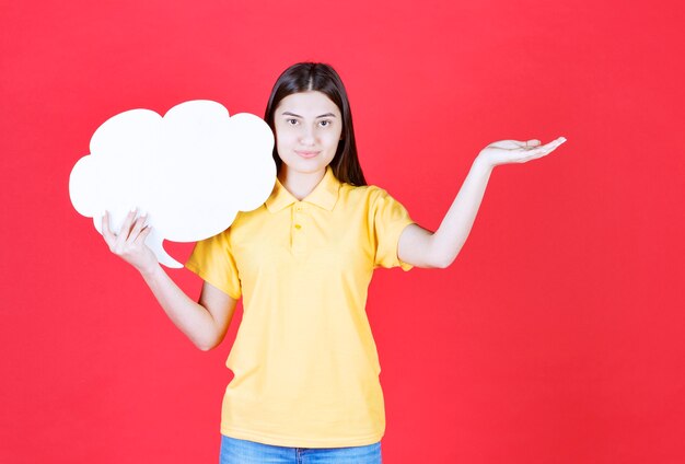 Chica en código de vestimenta amarillo sosteniendo un tablero de información en forma de nube