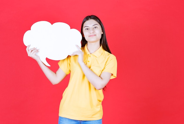 Chica en código de vestimenta amarillo sosteniendo un tablero de información en forma de nube