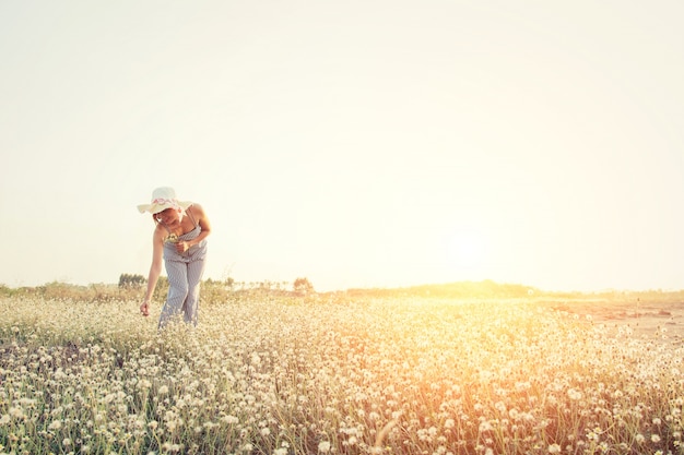 Chica cogiendo una flor en el campo