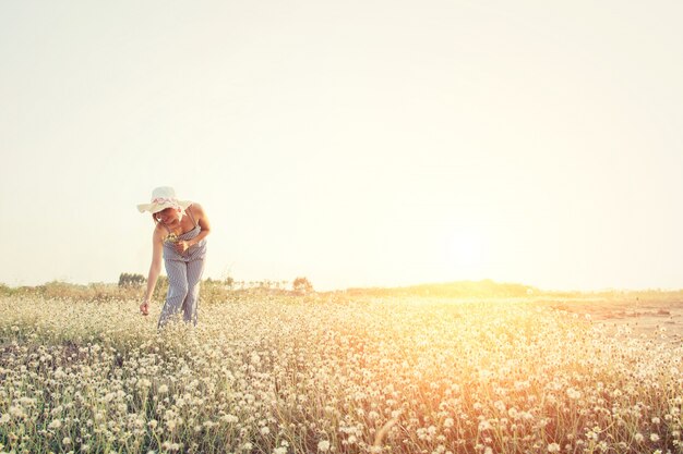 Chica cogiendo una flor en el campo