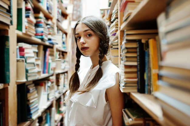 Chica con coletas en blusa blanca en la antigua biblioteca