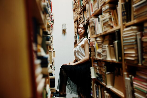 Chica con coletas en blusa blanca en la antigua biblioteca