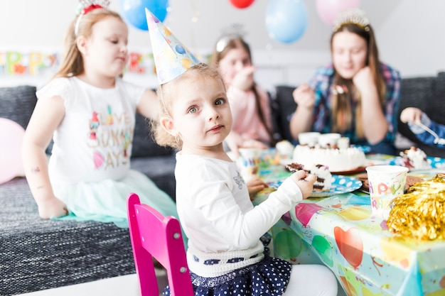 Foto gratuita chica comiendo pastel y mirando a la cámara