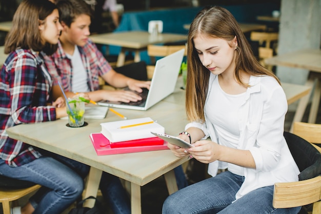 Chica con compañeros de clase en la mesa con la tableta