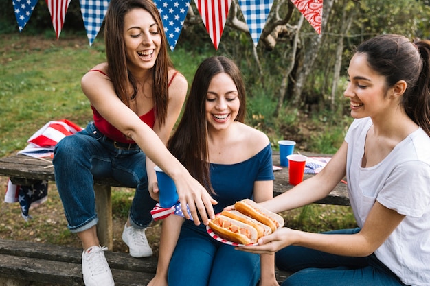 Chica compartiendo hot-dogs con amigos