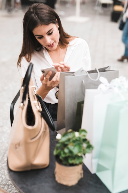 Foto gratuita chica de compras mirando el móvil