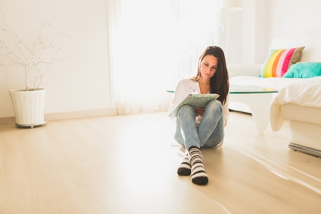 Foto gratuita chica concentrada escribiendo sentada en el suelo