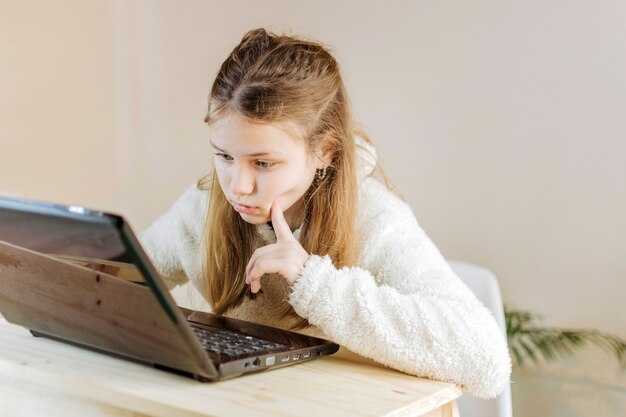 Chica concentrada usando la computadora portátil en casa