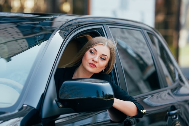 Chica conduce un coche y mira desde la ventana en el atasco de tráfico