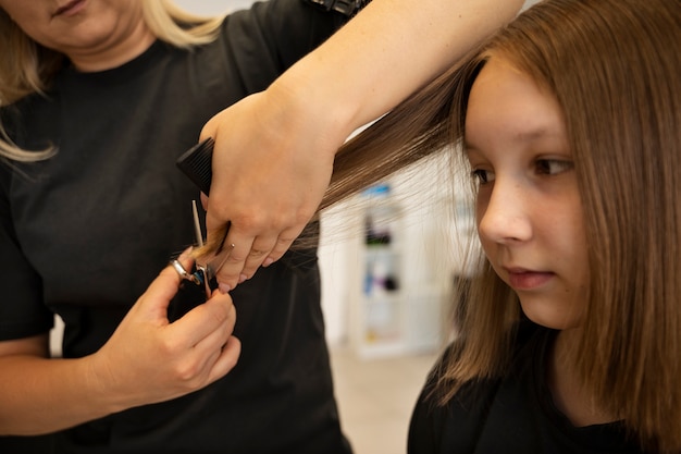 Foto gratuita chica cortándose el pelo en la vista lateral del salón