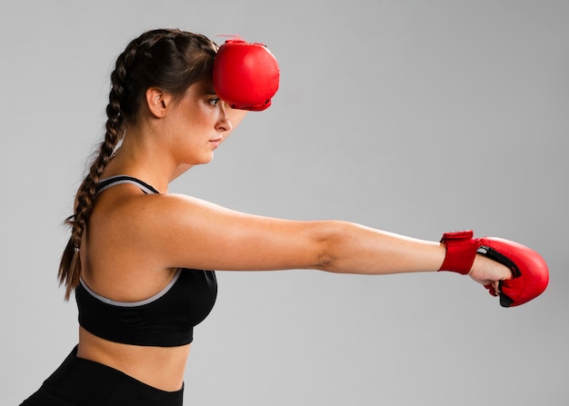 Chica de costado golpeando con guantes de box