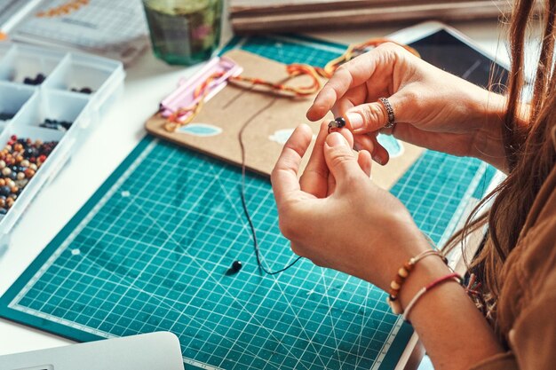 La chica creativa tiene un pasatiempo muy interesante: crea joyas con cuentas y piedras.