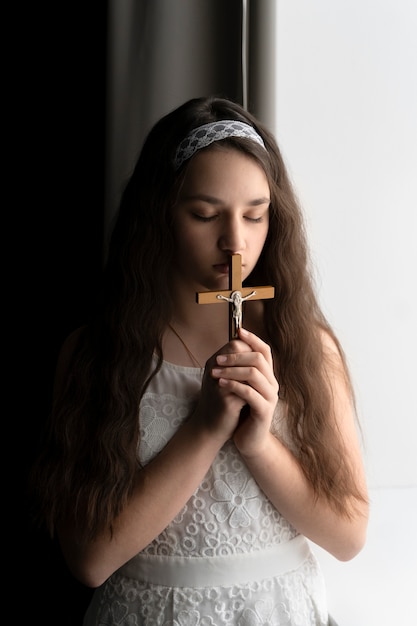 Foto gratuita chica cristiana de tiro medio rezando con crucifijo