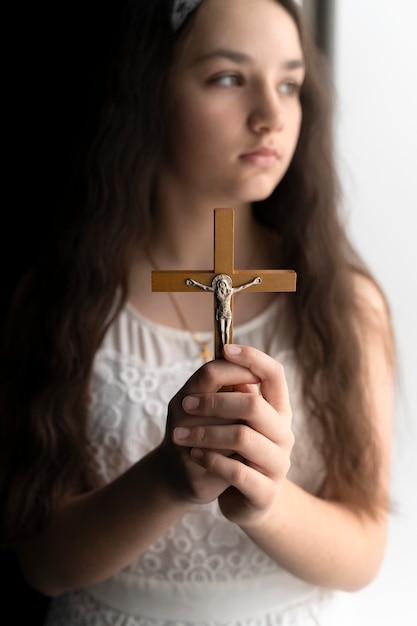 Chica cristiana de tiro medio sosteniendo crucifijo