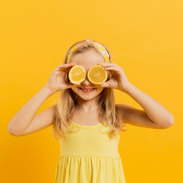 Chica cubriendo los ojos con rodajas de limón