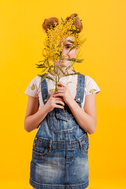 Chica cubriéndose la cara con ramas de flores